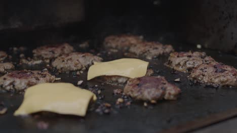 Adding-cheese-slice-on-top-of-frying-beef-meat-on-a-grill