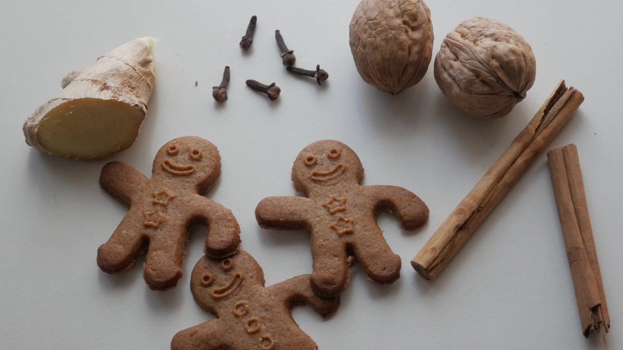 Biscotti di pan di zenzero con spezie e noci disposti su uno sfondo bianco per un allestimento festivo