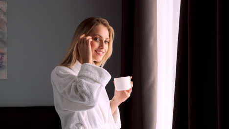 una mujer rubia bebiendo café en una habitación de hotel.