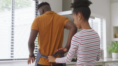 video of happy african american woman tying apron to her partner