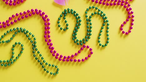 Video-Einer-Rosa-Maske-Mit-Mardi-Gras-Perlen-Und-Federn-Auf-Gelbem-Hintergrund-Mit-Kopierraum