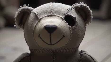 a charming teddy bear with a stitched design sits in a warm and inviting room. the sunlight filters through the window, casting soft shadows and enhancing the nostalgic atmosphere.