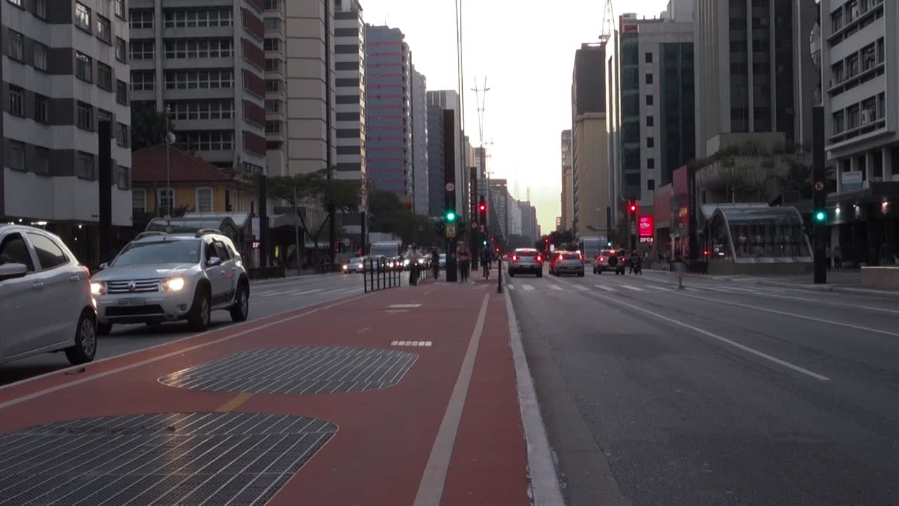 bike path in the middle of Avenida Paulista, in late afternoon. Cars and bikes coming and going, in slow motion