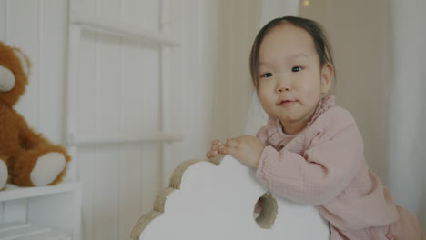 baby girl playing on wooden horse