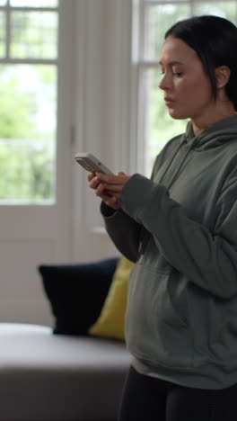 vertical video of stressed and worried woman with financial worries about cost of living crisis debt and paying bills at home looking at mobile phone