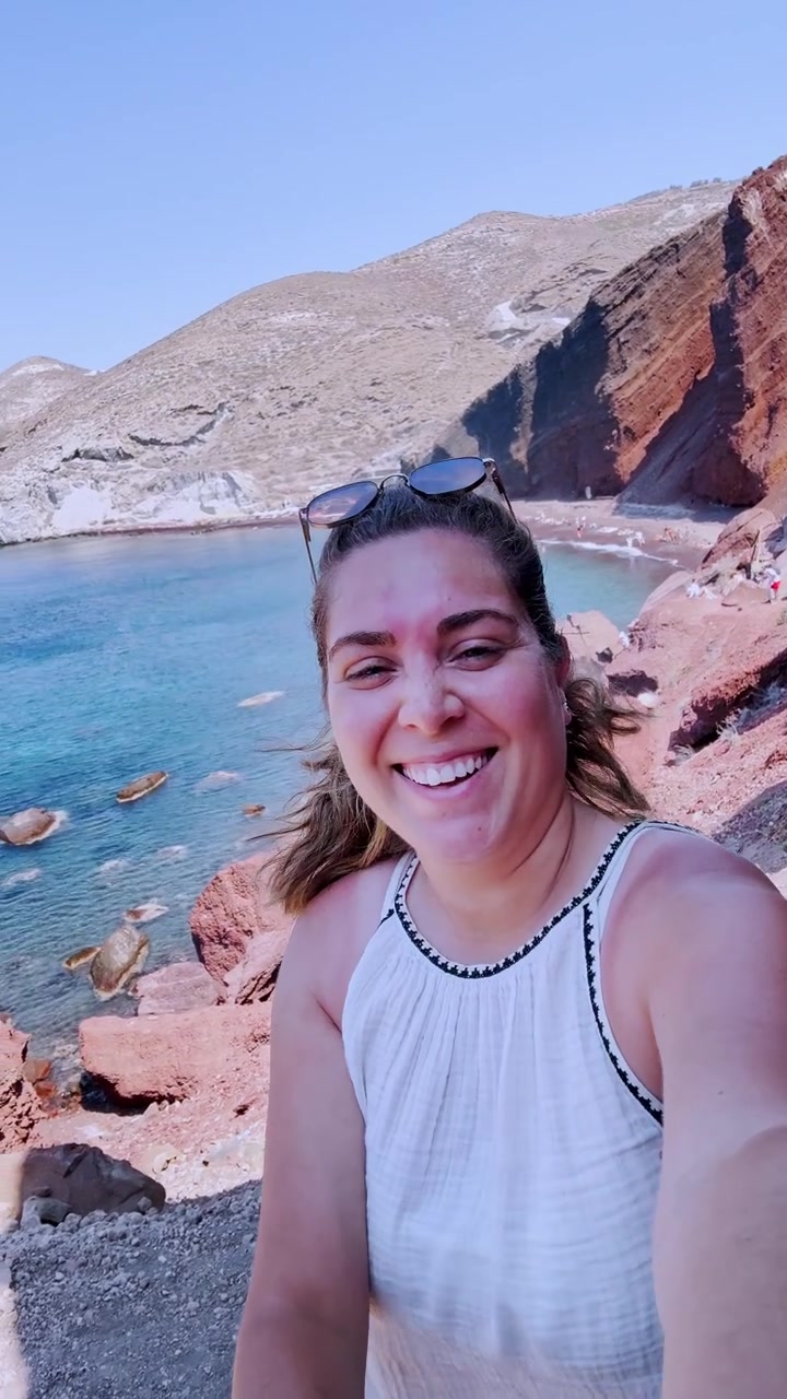 Nuori naisvloggaaja kuvaa selfie-videota Punaisella rannalla Santorinilla.