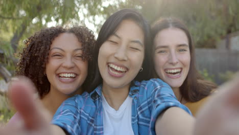 smiling and taking selfie, three young women friends enjoying outdoor time together