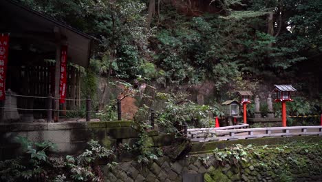 panoramique lent sur un petit temple japonais à l'intérieur de la forêt avec des piliers et des bâtiments en pierre typiques