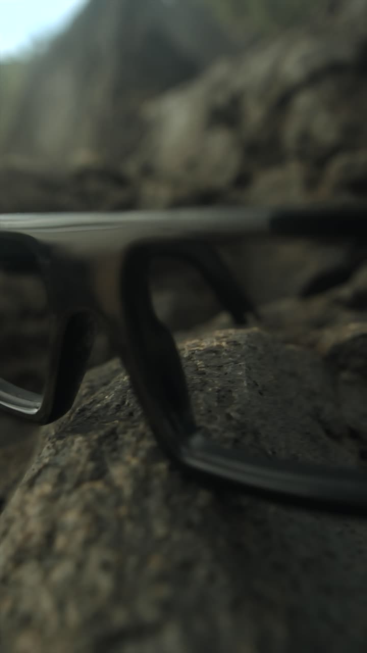 Glasses resting on a rock, close-up shot with a shallow focus highlighting details