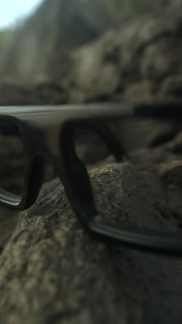 glasses resting on a rock, close-up shot with a shallow focus highlighting details