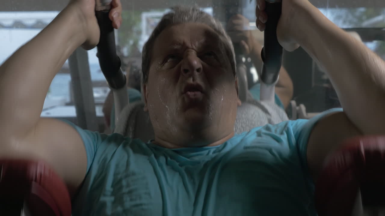 hombre adulto en camisa azul en el gimnasio realizando ejercicios en el abdomen superior