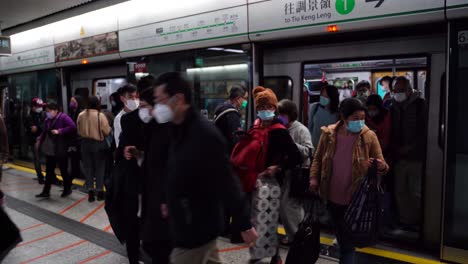 hong kong mtr station terminal, crowd of people with face masks going in and out of train, traffic jam in public trasnportation during covid 19 virus pandemic