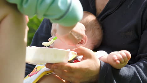 mother feeding a baby held by father