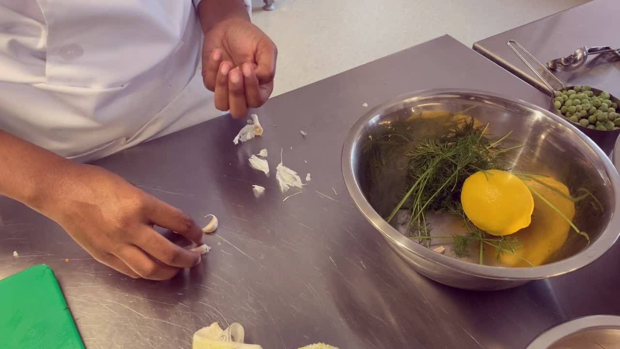 Young South African chef peels garlic cloves on stainless counter top