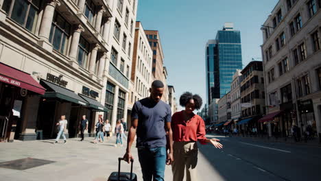 a couple exploring a city street with a suitcase and map
