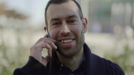 Front-view-of-smiling-young-man-talking-on-smartphone