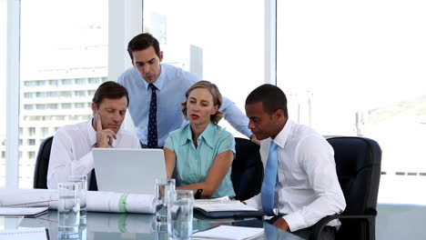 businesswoman explaining something to her colleagues while using a laptop