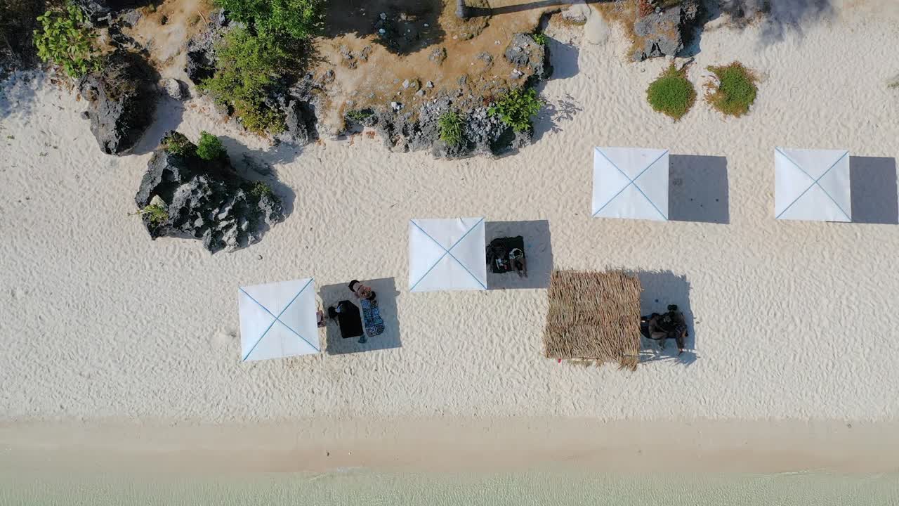 Bird’s Eye view of people under parasols at the tropical beach in Boracay. Relaxation, tranquility