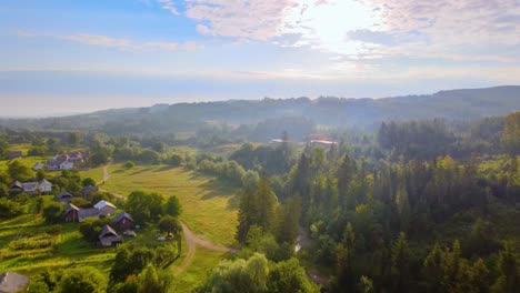 aerial view over road, houses and lush green nature, in the carpathian mountains, misty, summer day, in ukraine - tilt up, drone shot