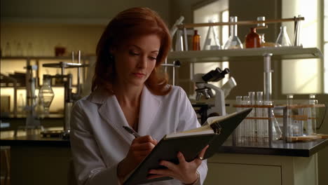 scientist in laboratory writing in notebook