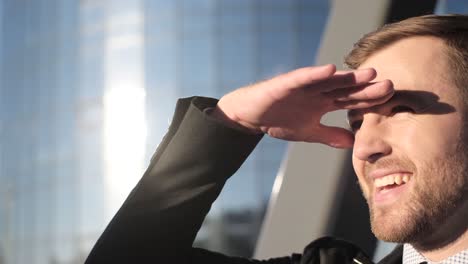 office manager closes his eyes and looks at the sun business man the office manager covers his eyes and looks towards the sun the businessman against the background of the glass business center