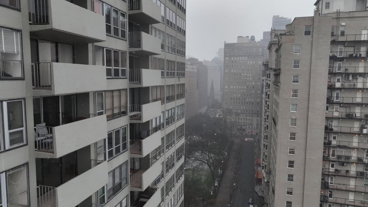 Torres residenciales en el centro en un día nublado de invierno, con vistas a una estrecha calle de la ciudad. Edificios de apartamentos de gran altura enmarcan un corredor urbano en condiciones frías y brumosas. Vista aérea en EE. UU.