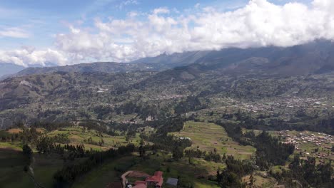 drone shot of houses and trees in the green hills and valleys of the peruvian andes