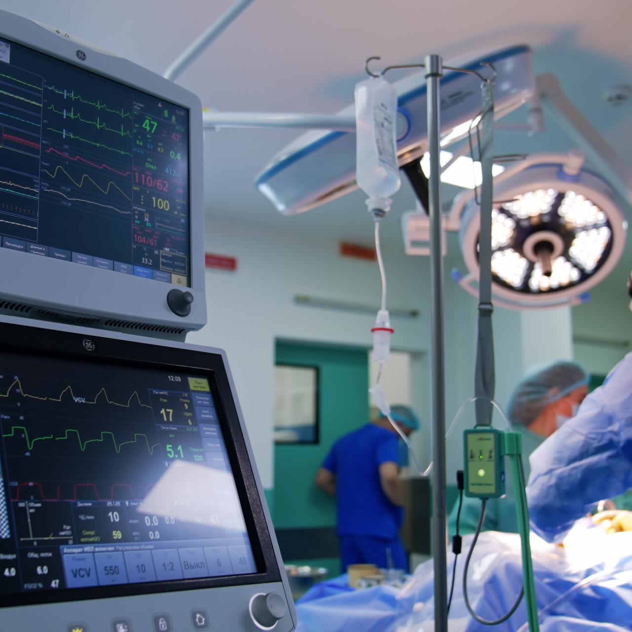 Monitore eines Beatmungsgeräts zeigen die Vitalfunktionen des Patienten an. Rückansicht eines Neurochirurgen, der an einem OP-Tisch im Hintergrund steht