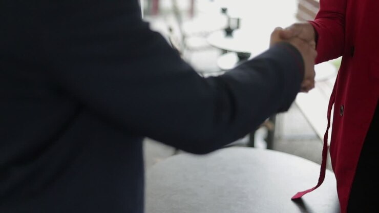 Medium shot of womans and mans shaking hands, making deal