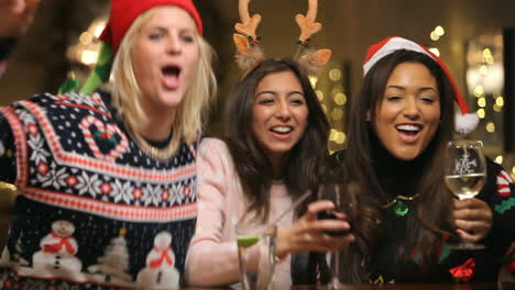 grupo de amigas disfrutando de bebidas navideñas en un bar