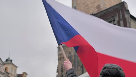 czech national flag waving in hand of male, old town prague during protest, slow motion close up