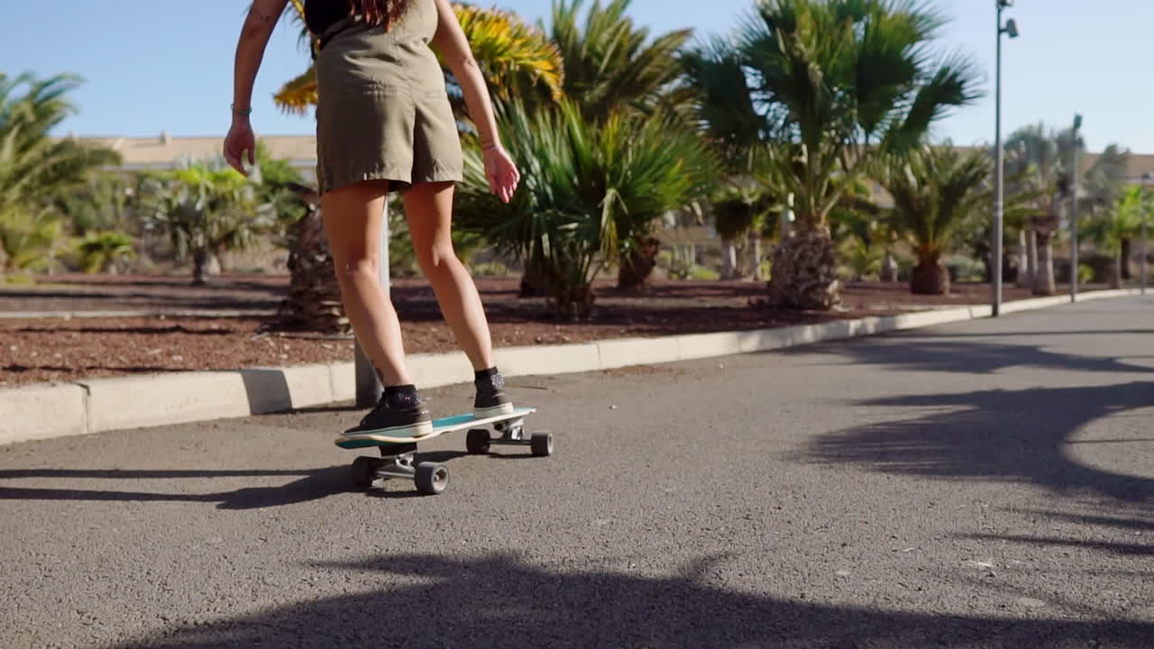 Amidst the tranquility of palm trees and the beach, a young girl's longboard journey is showcased in slow motion, embodying both beauty and relaxation