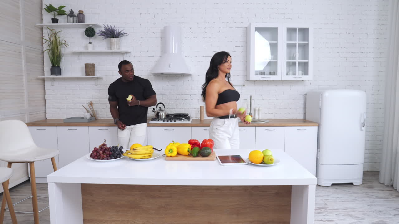 Casal se divertindo na cozinha com frutas