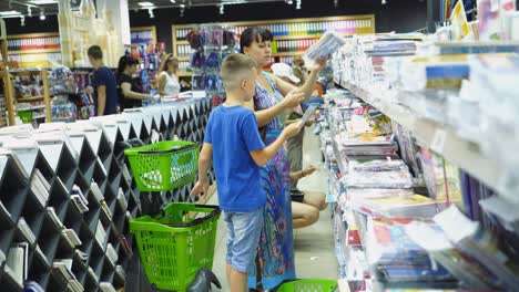 vinnitsa, ukraine - august 20, 2018: back to school concept. young mother and little boy buying school supplies in store.