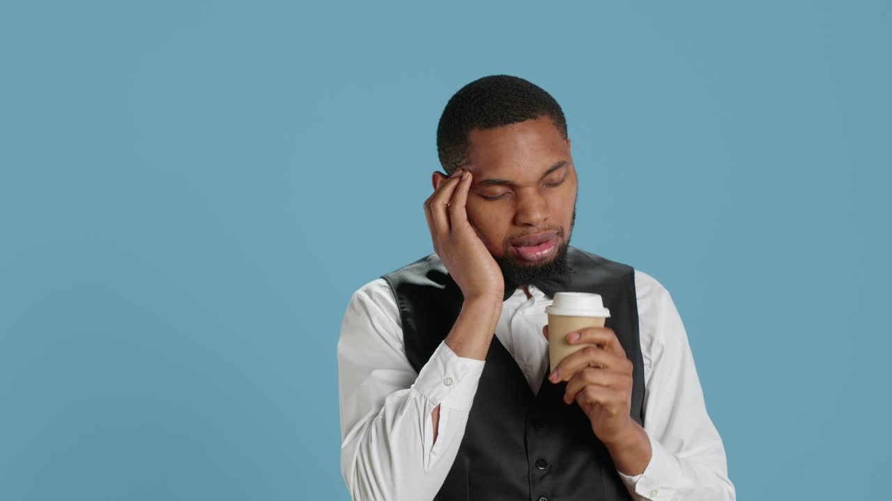 Unwell hotel porter feeling sick and drinking a cup of coffee