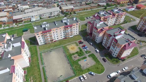 beautiful view of newly built complex with cars in the streets and green grass near the buildings. camera moves back. aerial view
