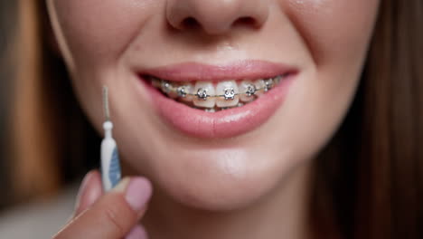 mujer con aparatos ortopédicos y cepillo interdental