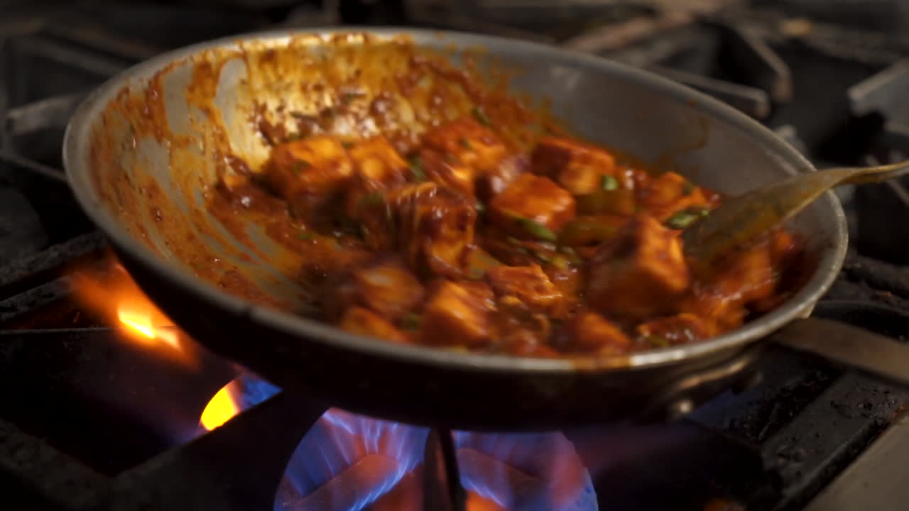 Paneer tikka masala saltato in padella sul fuoco nella cucina di un ristorante, primo piano in slow motion 4K.