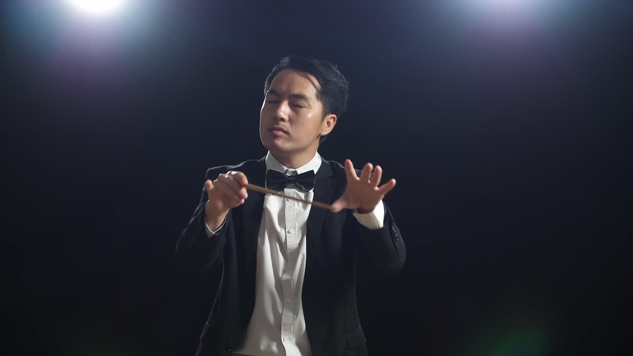 흑인 스튜디오에서 눈을 감고 몸짓을 하는 아시아인 지휘자