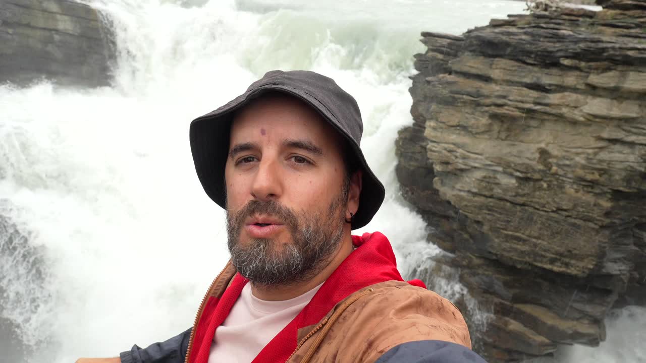 Mand, der tager selfie i nærheden af et vandfald