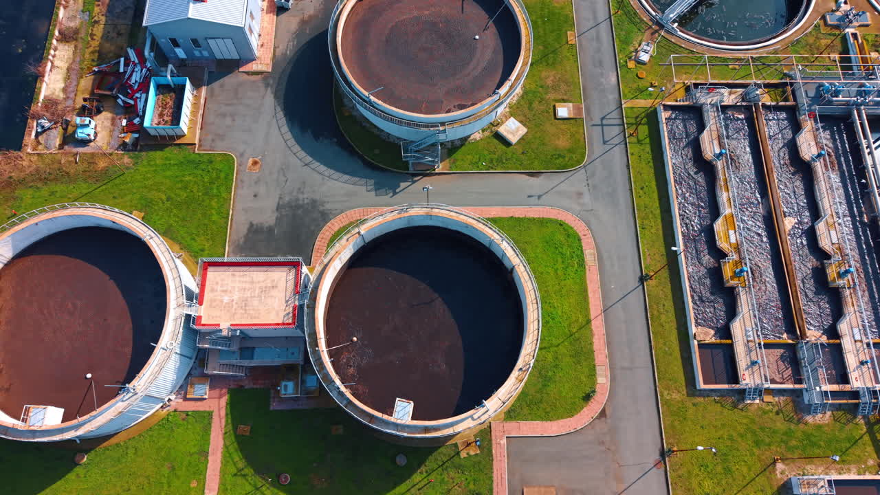 Top down aerial view of water treatment facility tanks. Vertical top down shot showing circular clarifiers and rectangular basins at a plant