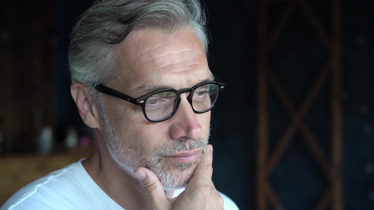Thoughtful Mature Man Wearing Glasses Looking Down