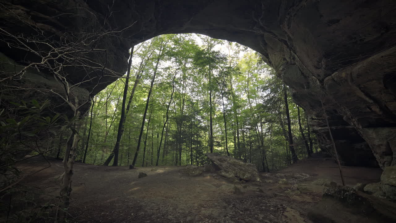 excursionista femenina camina bajo un enorme arco de piedra natural en el bosque de tennessee, 4k