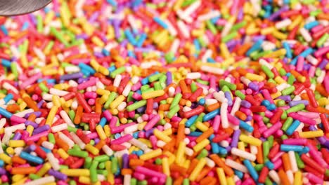 spoon scooping vibrant sprinkles from a pile