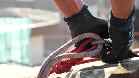 Worker-hands-securing-life-rope-in-a-construction-site-roof-closing-a-carabiner