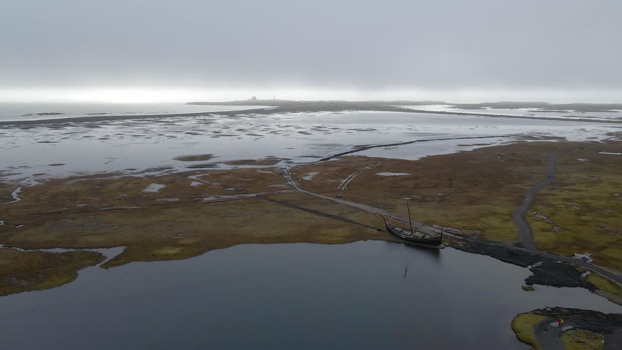 drone flyover viking barco amarrado en la laguna, playa de arena negra, vestrahorn, islandia