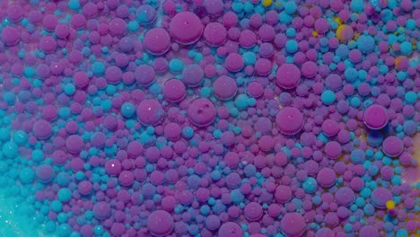 Ink bubbles mixed with liquid substance of oil, milk, soap, bright acrylic paint on colorful surface