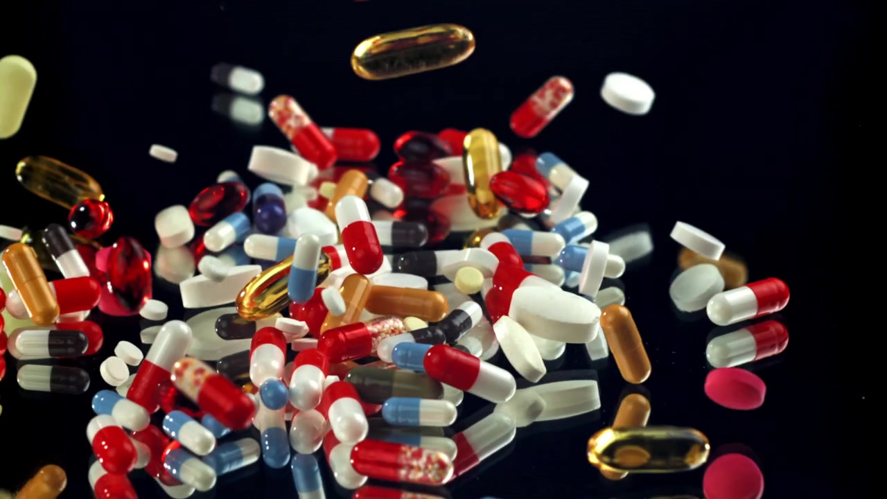 Assortment of Colorful Pills and Capsules Falling onto Black Surface