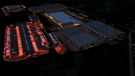 aerial view of the large logistics park with warehouse, loading hub with many semi-trailers trucks standing at the ramps for load unload goods at night
