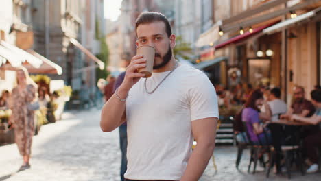 young man guy enjoying drinking morning coffee hot drink relaxing taking a break in city street